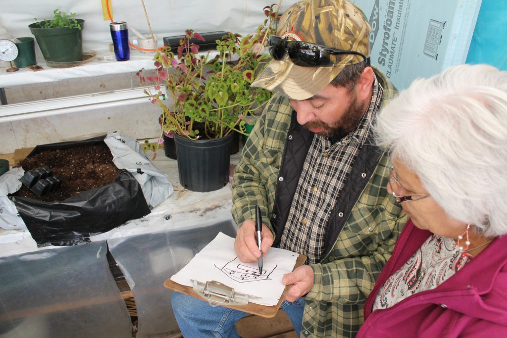Robert from Thicket Portage and Caroline from Wabowden mocking up a greenhouse design together. Both Robert and Caroline grew up strong in their tradition of country foods (trapping and hunting) and attended the workshop to learn additional ways, like growing greenhouse vegetables, to increase access to healthy foods in their communities. 