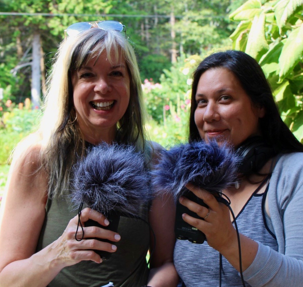 Two women holding up microphones with fuzzy windscreen to record for podcast workshop.