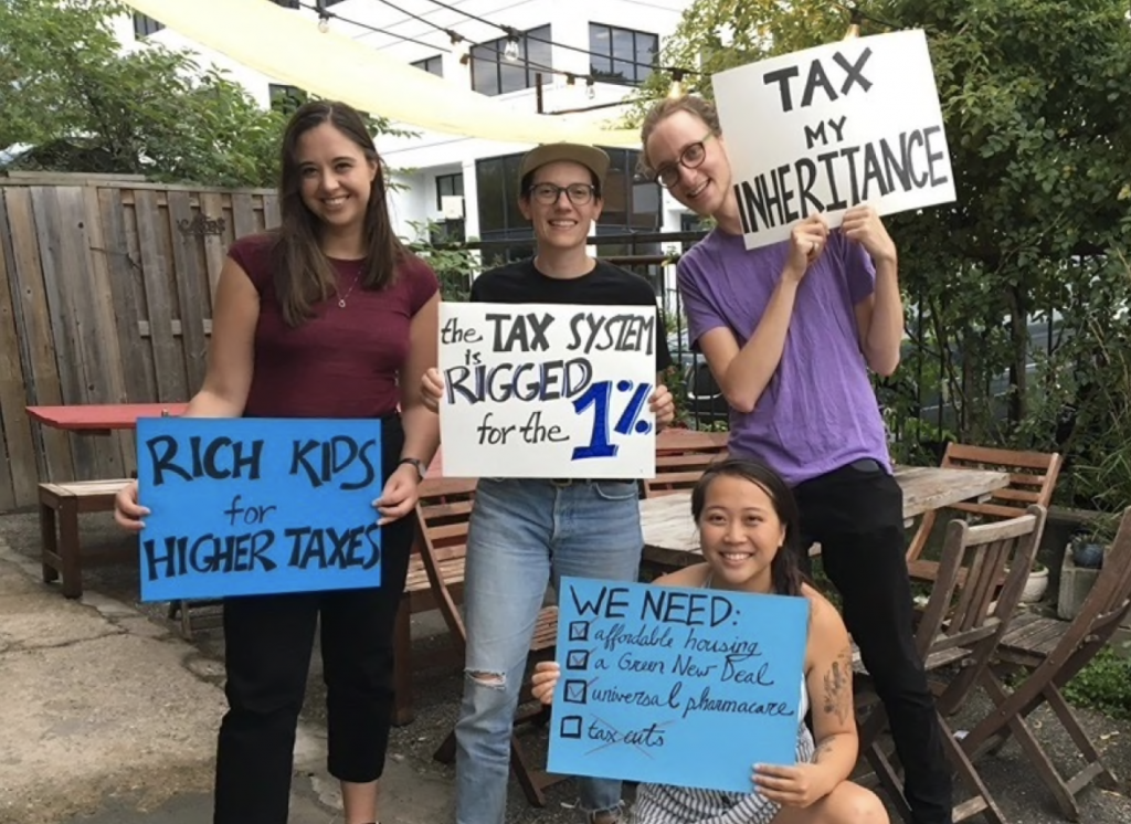 Youth hold signs entitled "tax my inheritance"