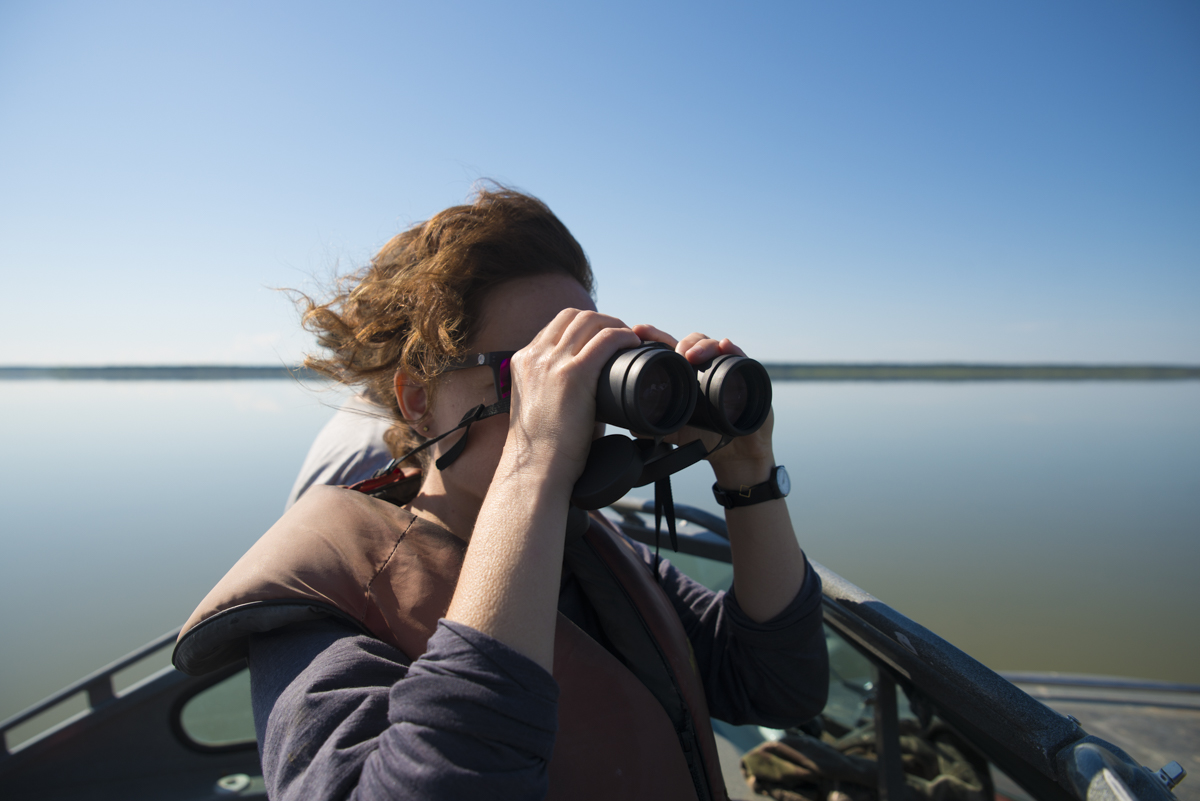Person on a looking through binoculars on a boat on Mackenzie River